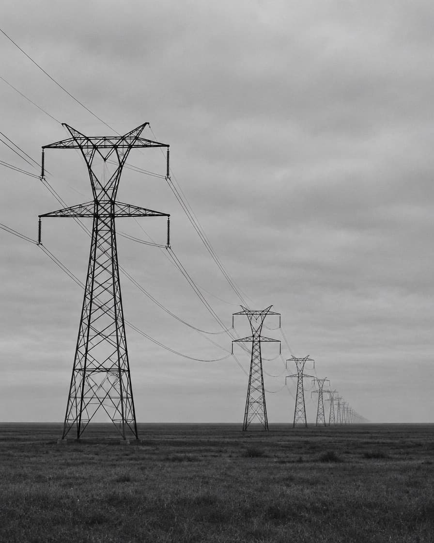 Line of high-voltage transmission towers crossing open terrain